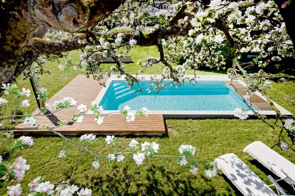 Ein naturnaher Poolgarten unter blühenden Ästen