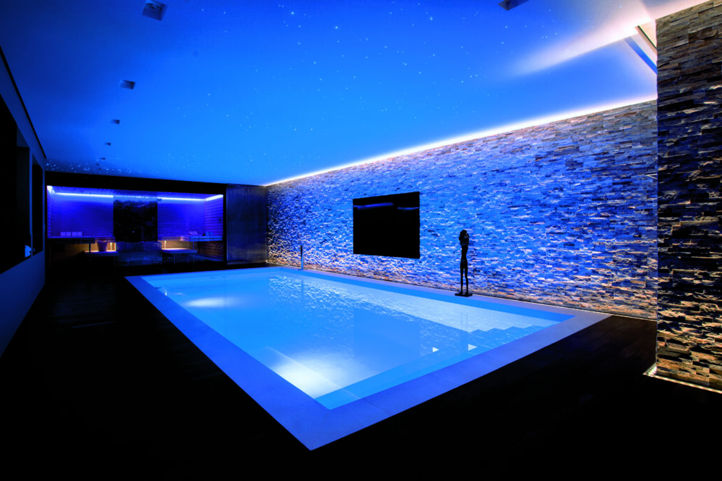 Indoor-Pool mit blauer LED-Beleuchtung und Steinwand