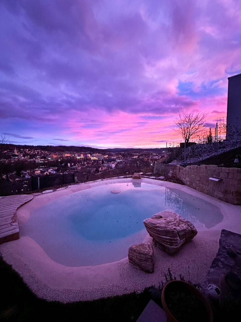 Abendlicher Blick auf den Pool mit mediterraner Natursteinmauer