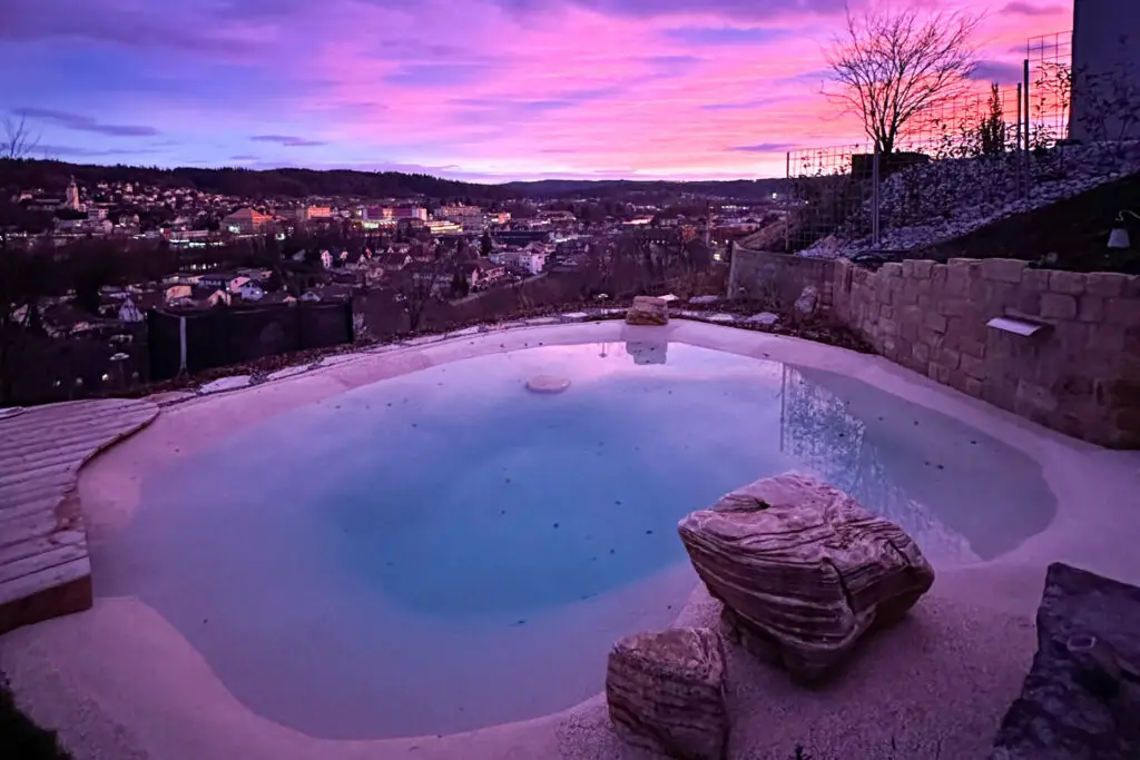 Abendlicher Blick auf den Pool mit mediterraner Natursteinmauer