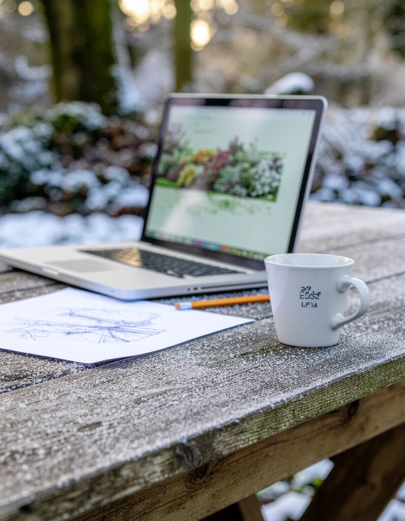 Gartenplanung im Winter mit Laptop und Zeichnung