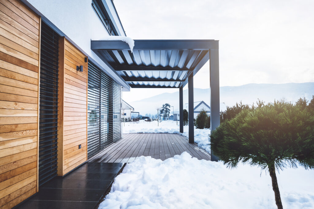 Moderne Terrasse im Winter mit Schnee und Bergkulisse.