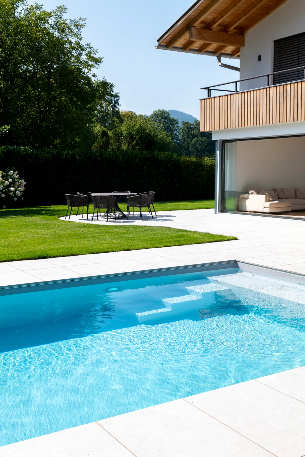 Moderner Pool mit integrierten Stufen und klarer Linienführung im Garten