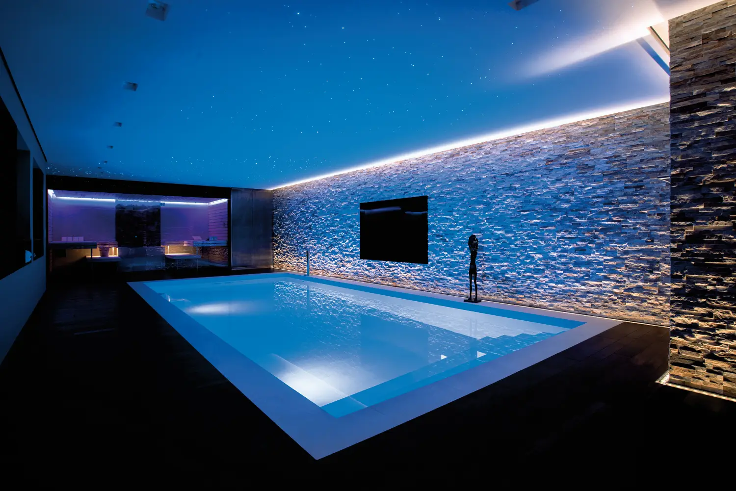 Moderner Innenpool mit blauer Lichtstimmung und Steinwand, Foto aus dem BEHNCKE-Landingpage-Material